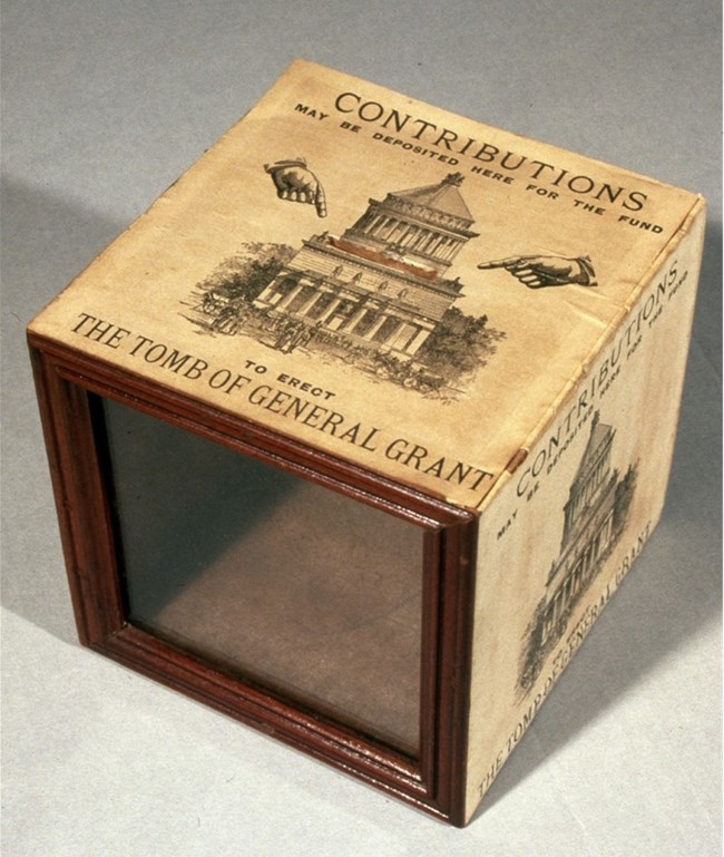 Brown box with a drawing of a large tomb with columns and text above and below