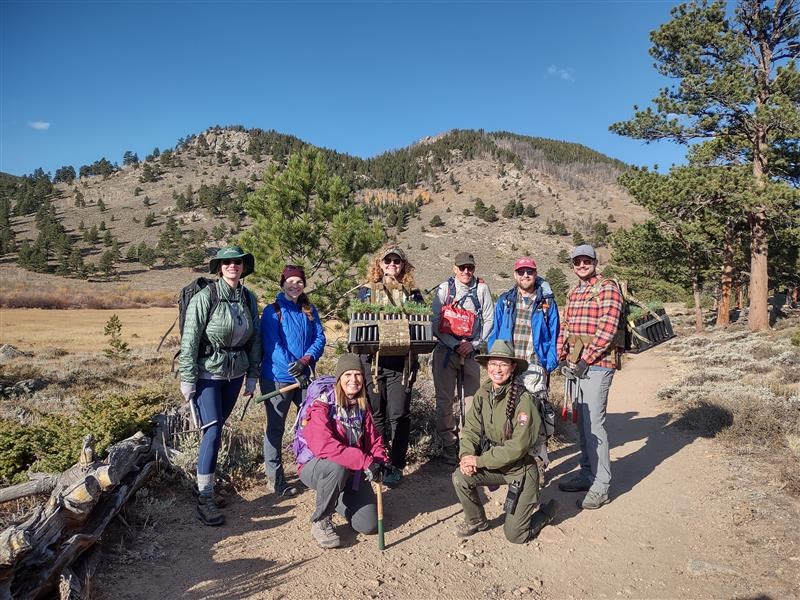 A group of NPS staff and volunteers are pictured standing outside while working on a limber pine planting project