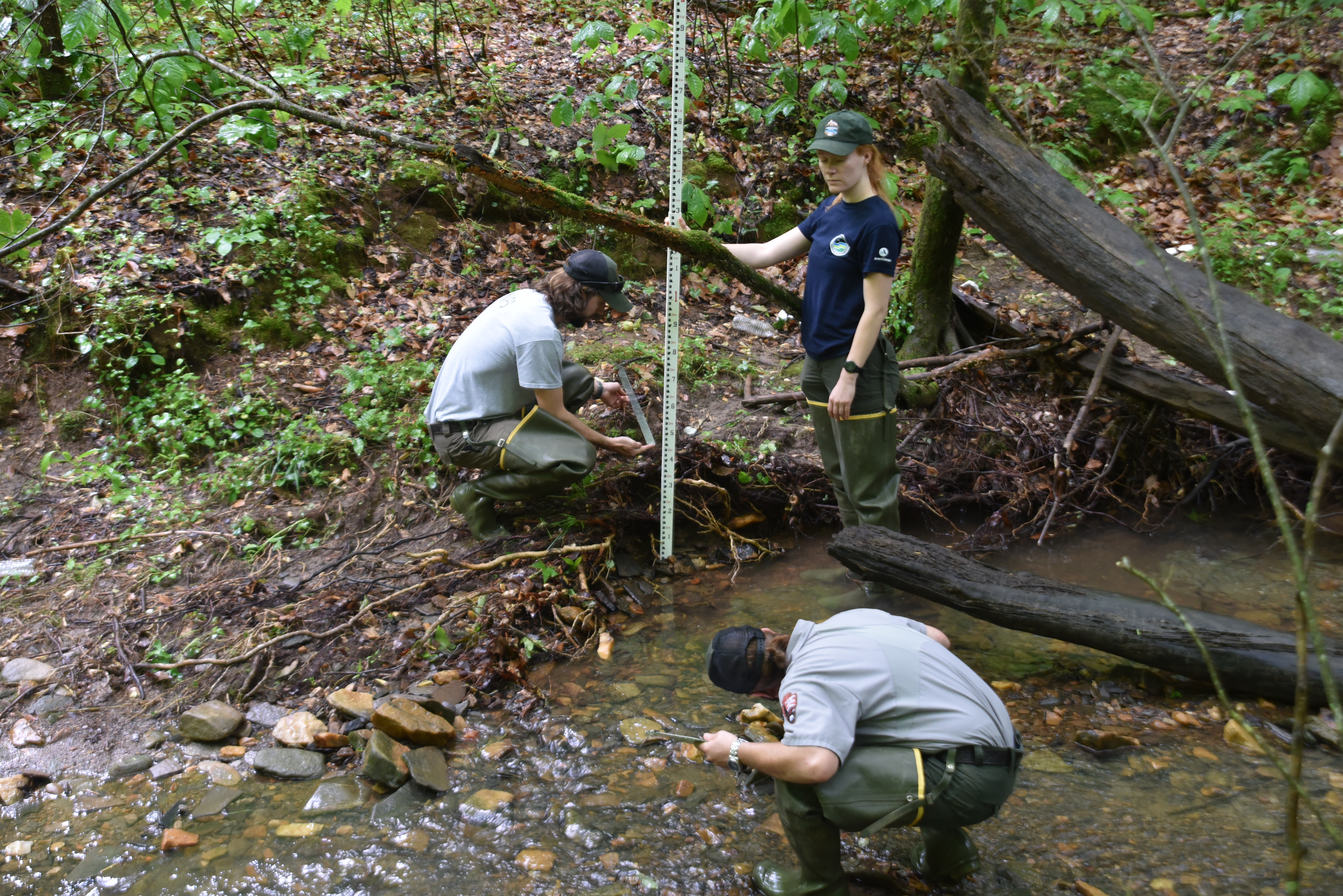 Woman holds measuring stick while a man squats down in front to read it.