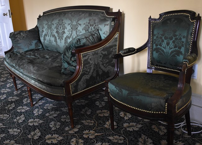 A mahogany couch and chair, upholstered in green silk.