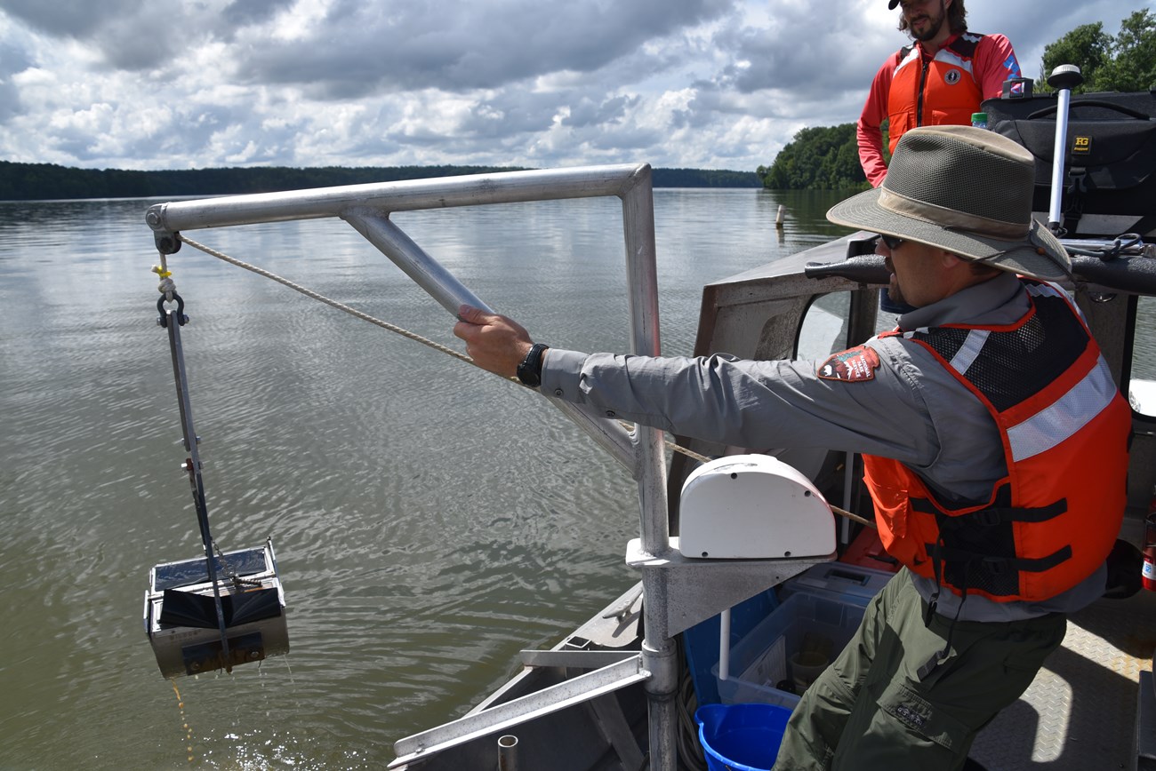 Man pulls grab sampler onto a boat