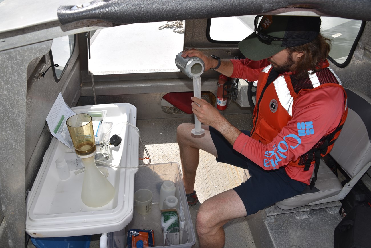 Man pours a liquid into a graduated cylinder