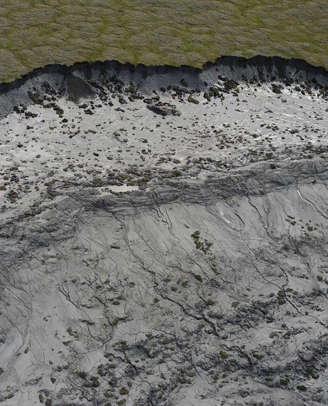 An aerial view of a thaw slump showing earth broken away and mud slide.