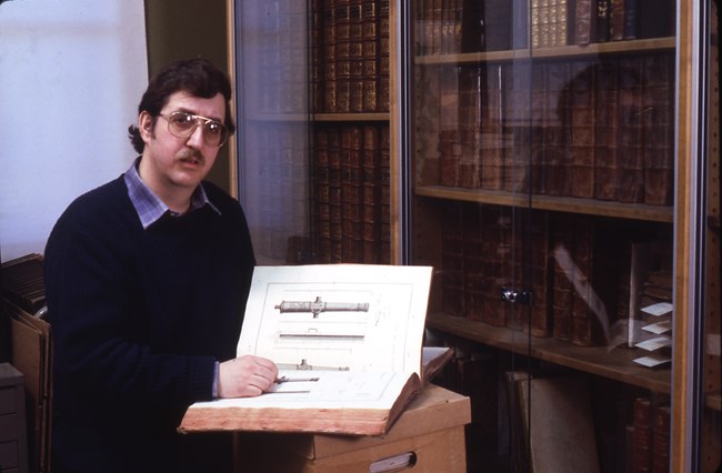 David Nathanson sitting in a library with an open book in front of him