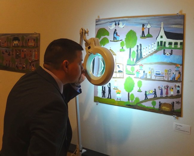 FBI Special Agent Randy Deaton examines a Toye forgery of a Clementine Hunter painting.