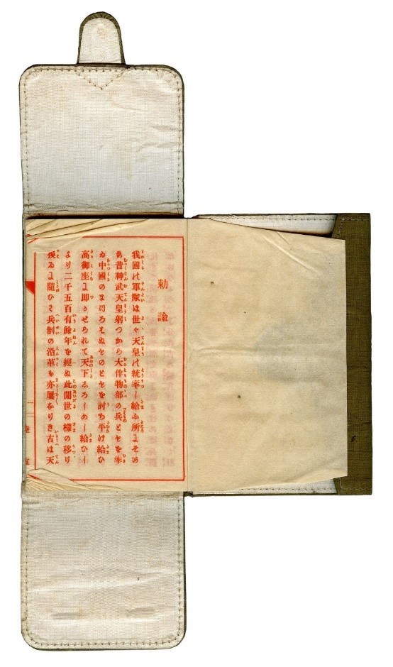 A leather wallet that folds in three places. The wallet is white, and unfolded. In the center area are papers with Japanese writing. There is a flap that folds over the center papers, and the two smaller flaps that fold over each other to close.