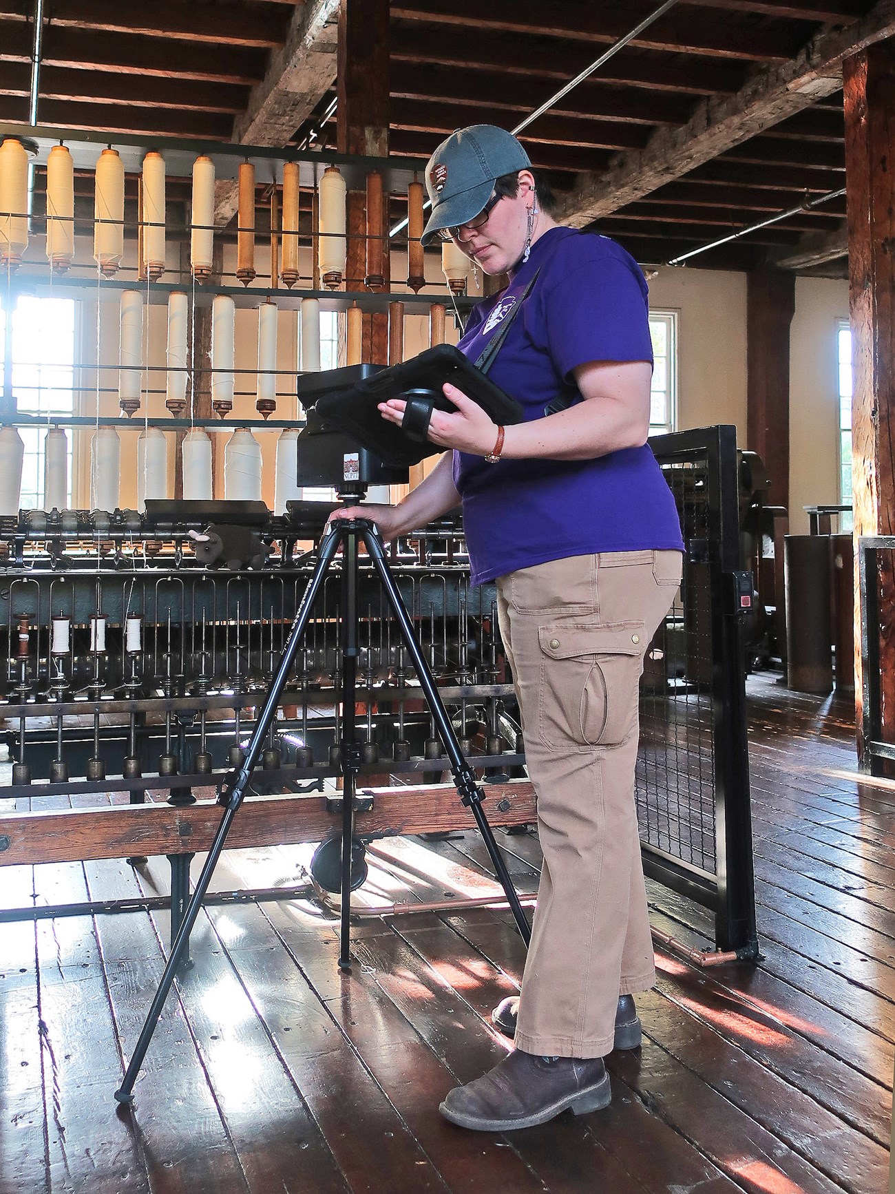 Cooper positioning the child height camera in front of a spinning machine with one hand and holding an iPad in the other.