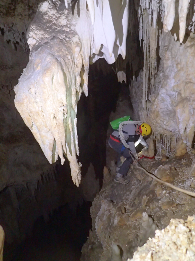a person walking along a ledge in a cave