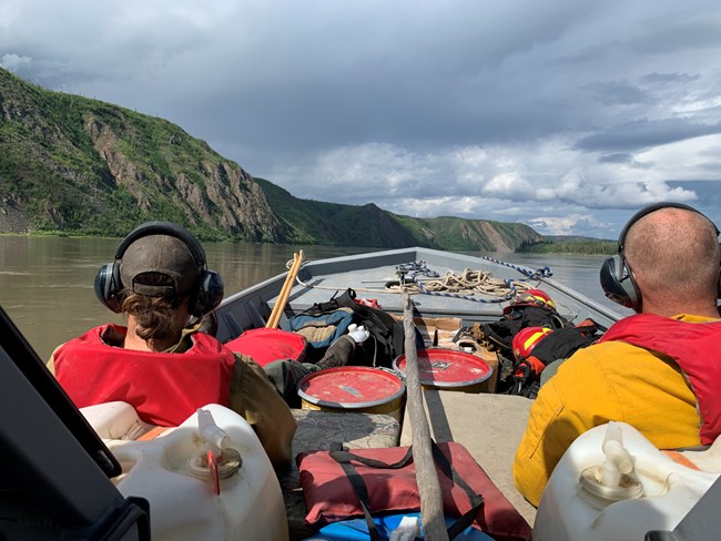 Two people riding in a boat stacked with fire gear and equipment.