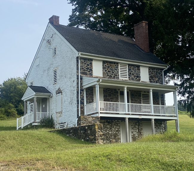 A two-story fieldstone farmhouse. Built into a green embankment on a hill.