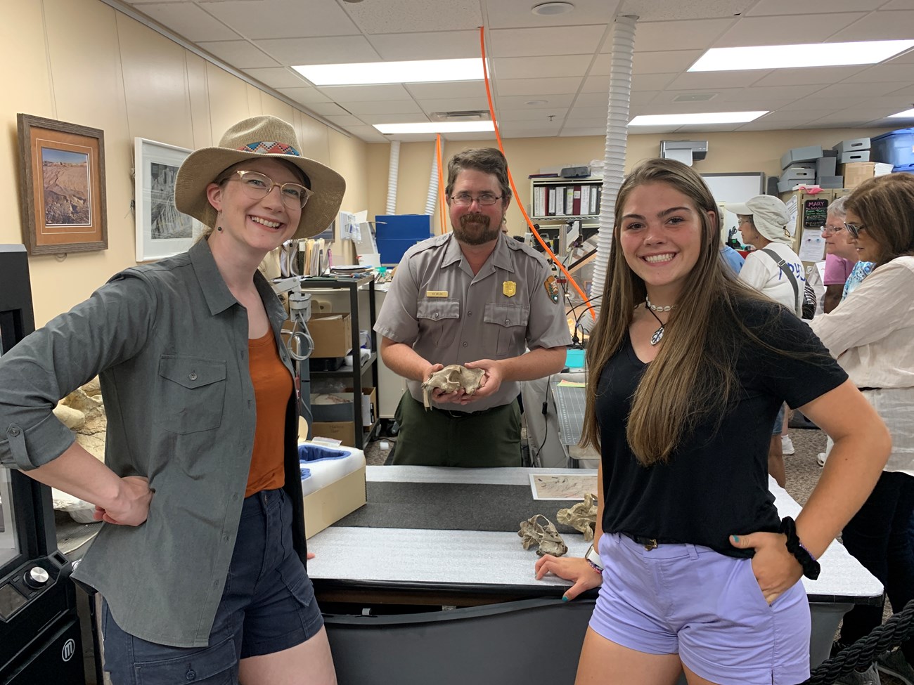 three people standing near a table in a fossil laboratory