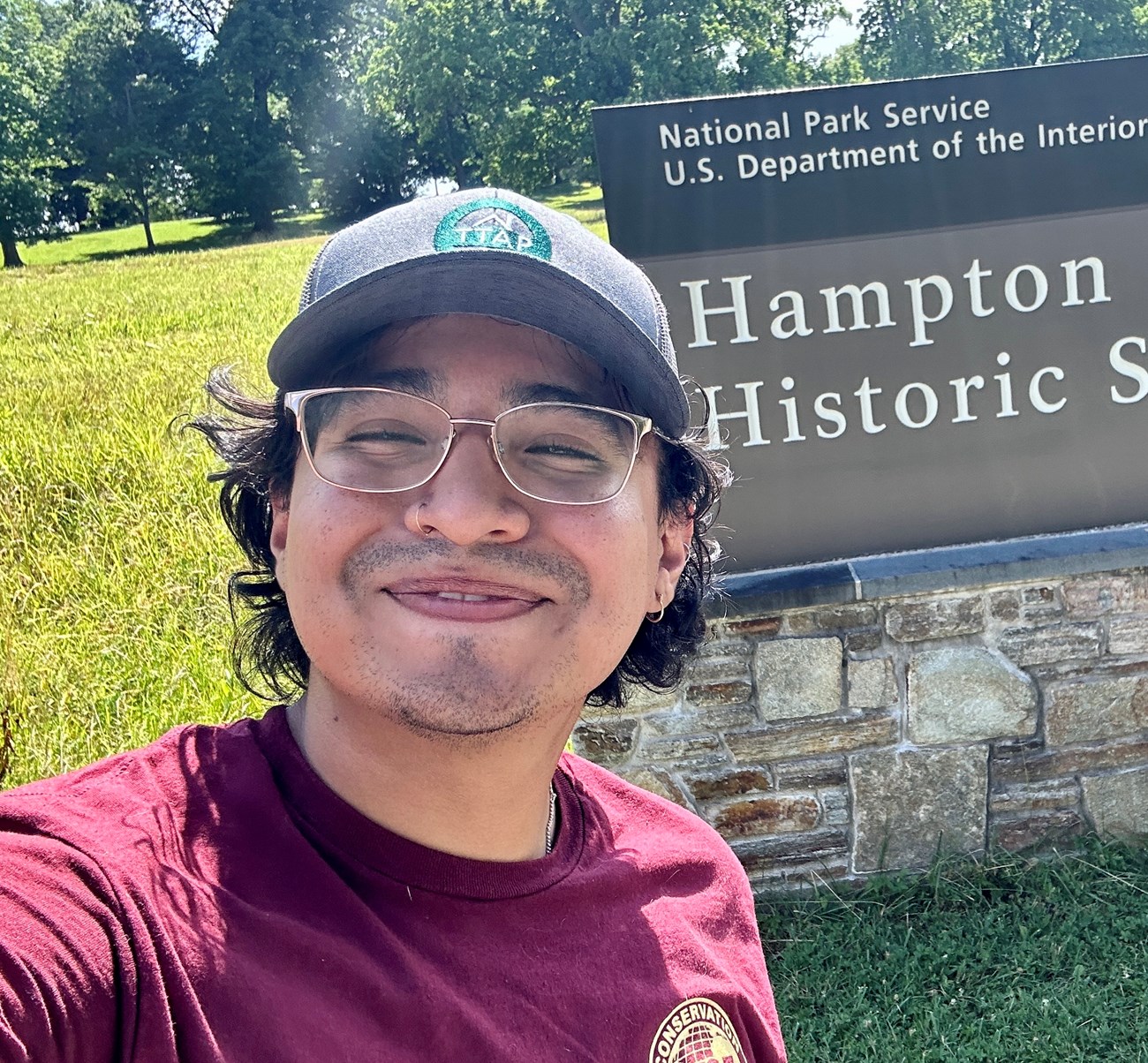 Intern Erick Contreras smiles for a selfie in front of the Hampton National Historic Site sign