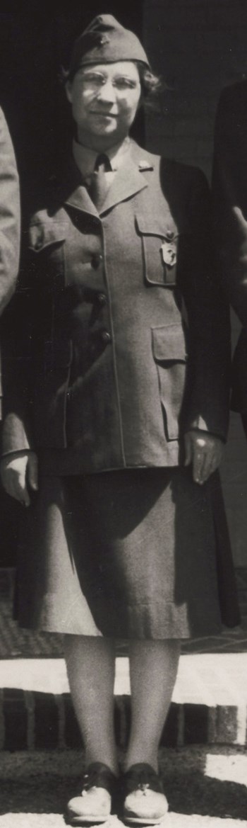 A women in a flight cap, buttoned down jacket with NPS badge pinned to her chest, dark skirt, stockings and dark shoes.