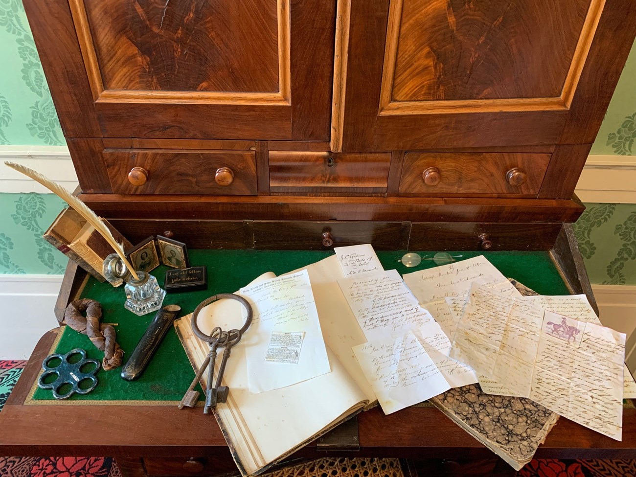 Writing instruments and parchment sit on a 19th century desk