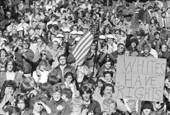 A crowd of people with an American flag and a sign that reads "Whites have rights"