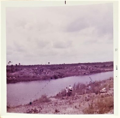 Photo of two people standing at the edge of a waterway.