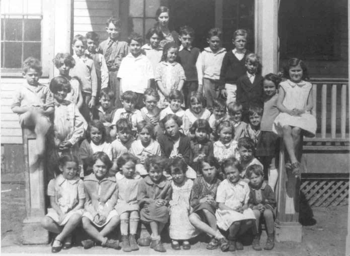 a group of young children sit on schoolhouse steps