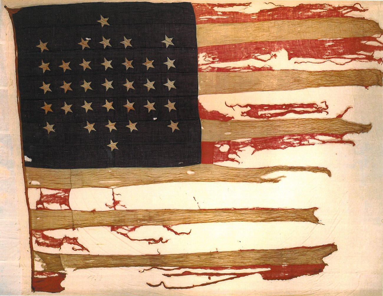 A tattered United States flag bearing 33 stars.