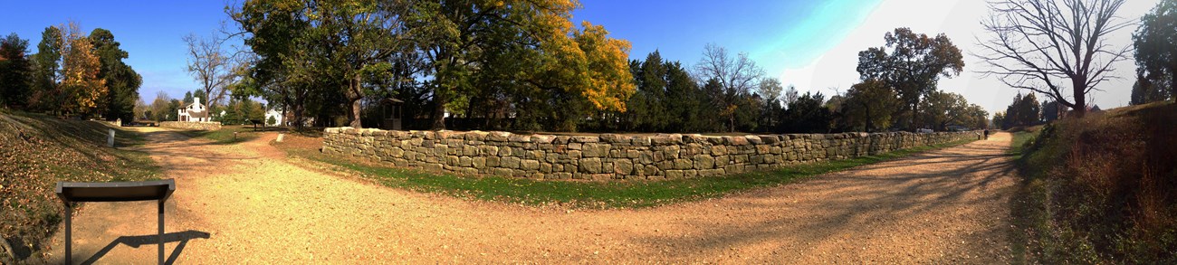 A stone wall along a gravel road.