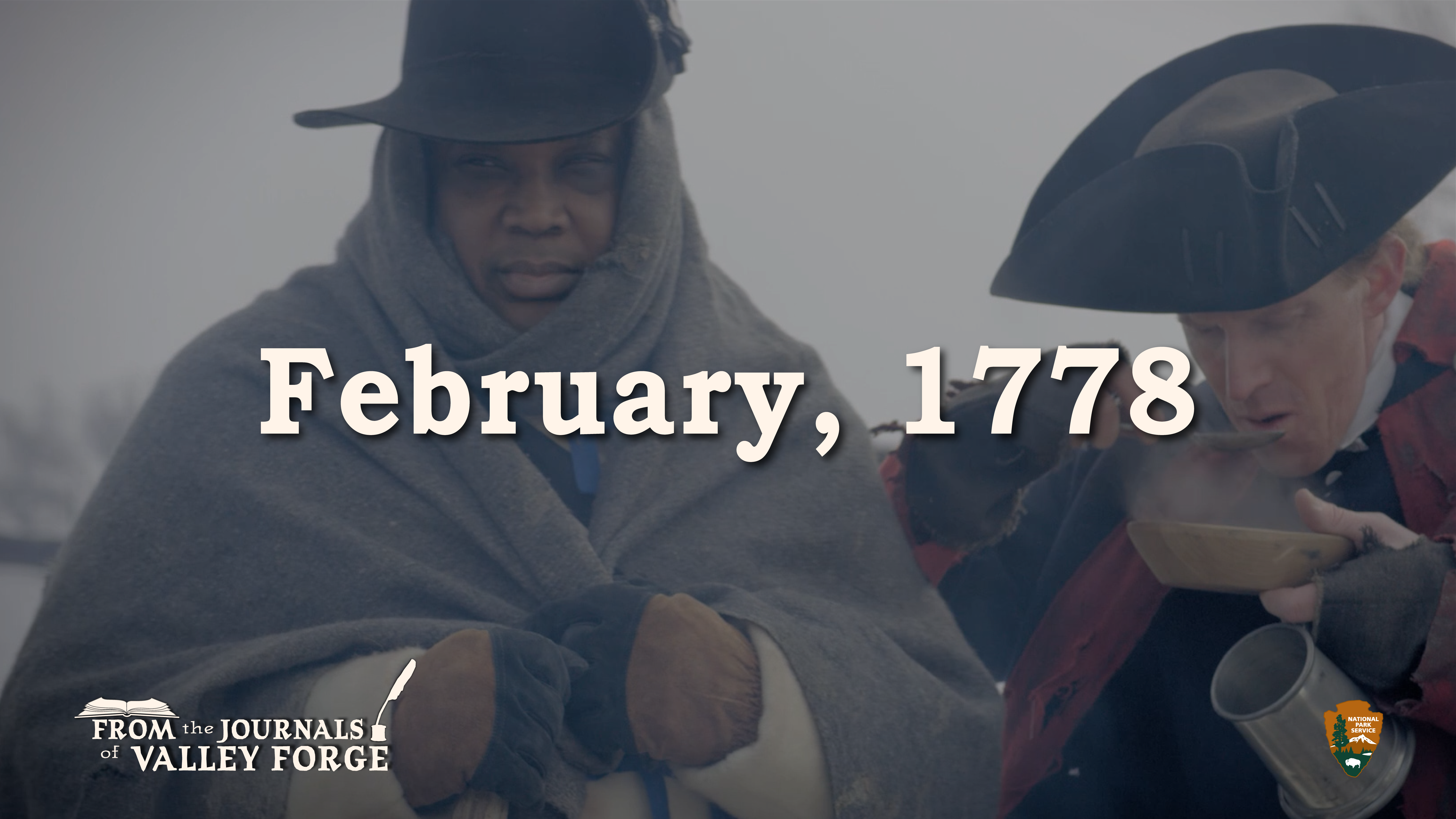 A man stands wrapped in a blanket on the left and on the right another man spoons a steaming liquid into his mouth.