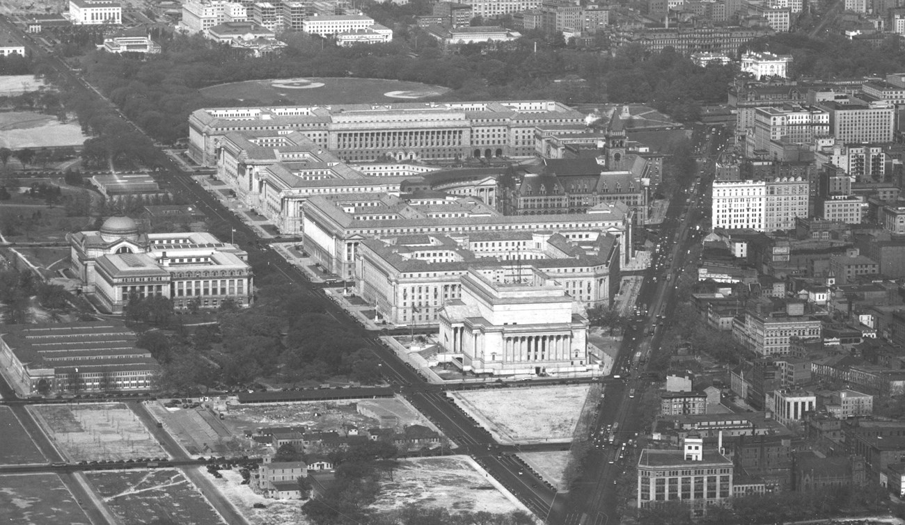 A black and white aerial photo of the federal triangle after it was constructed. The point of the triangle is in the foreground, showing the National Archives building in full.