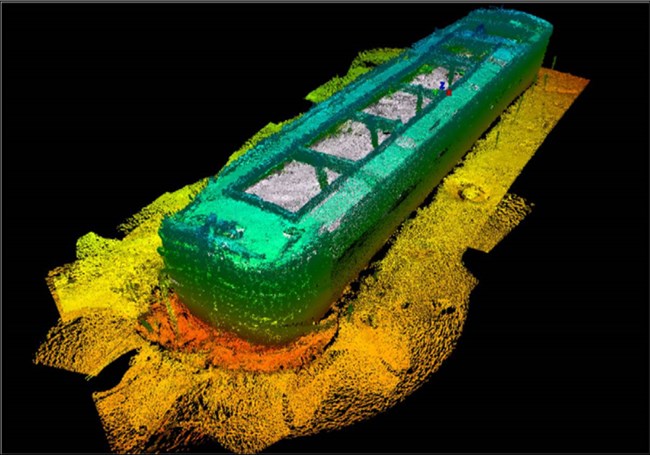 A false color image of the Sloop Island Canal Boat (VT‐CH‐843), which appears as a coffin-shaped blue and white object laying on a lakebed shaded in yellow and orange topographical relief.