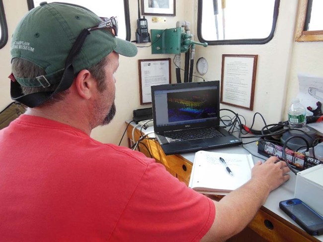 Figure 6: LCMM Archaeologist reviewing sonar data aboard the RV Baldwin during the 2012 survey (LCMM Collection).