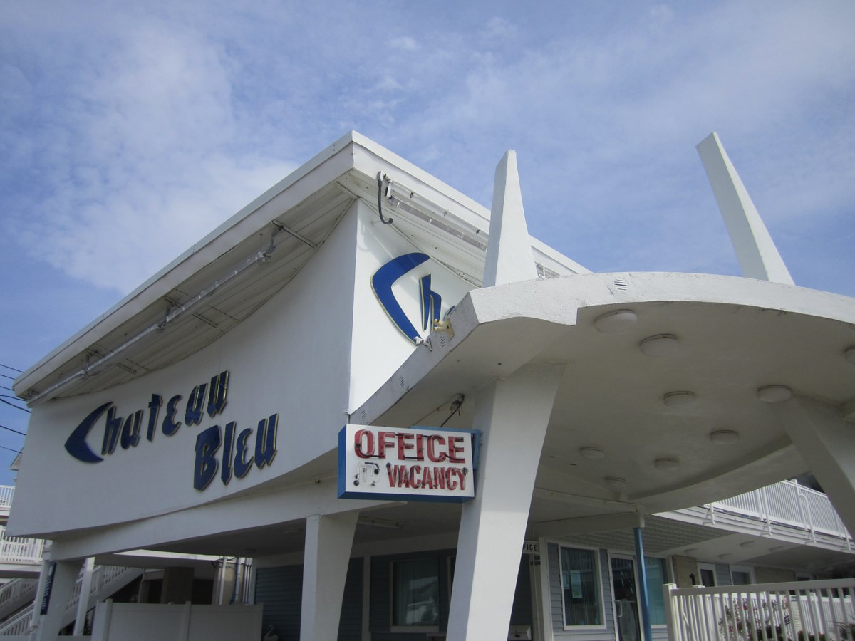 White mid-century modern motel covered entry sign reads Chateau Blue Office Vacancy.