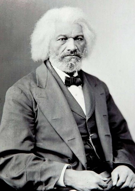 An aging, white-haired, African American man, Frederick Douglass, sitting.