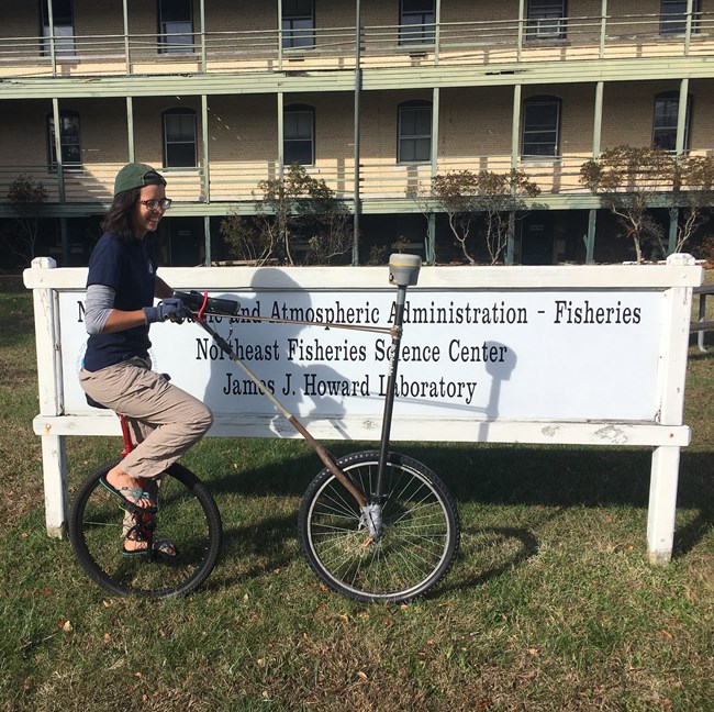 intern stands in front of workplace sign