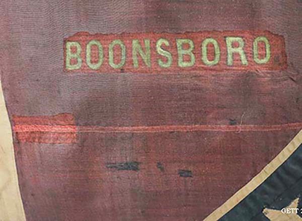 The word "Boonsboro" seen in yellow on a red fabric background with part of a blue section of fabric intersecting the bottom right corner.