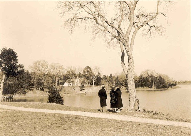 people overlooking Popes Creek with building in distance and footbridge to the left