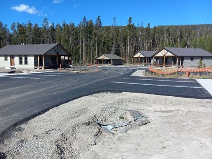 Prototype housing at Grand Teton National Park with paved road and parking area in foreground.