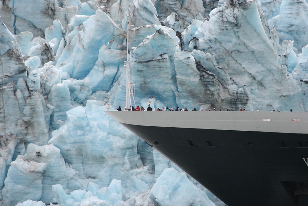 A large cruise ship noses in close to the face of a tidewater glacier.