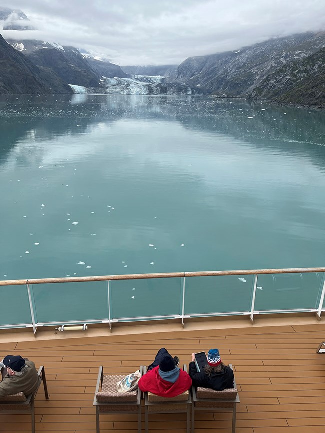 People on a cruise ship deck enjoy a longer view of a glacial inlet.