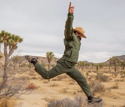 A park ranger jumps through the air in the desert.