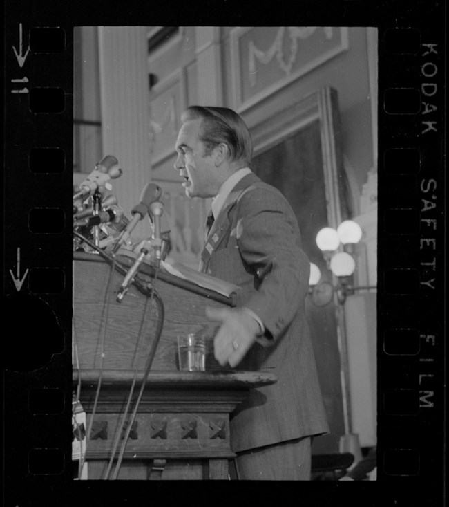 Black and white photo of George Wallace speaking on stage at Faneuil Hall
