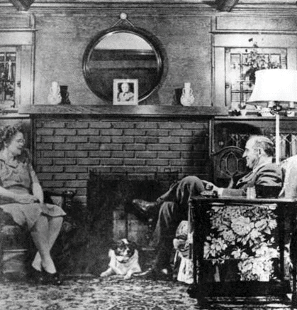 Picture of George and May Wallace sitting inside their home by a fireplace