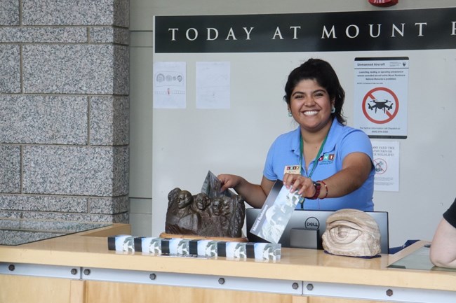A woman hands out park maps to visitors