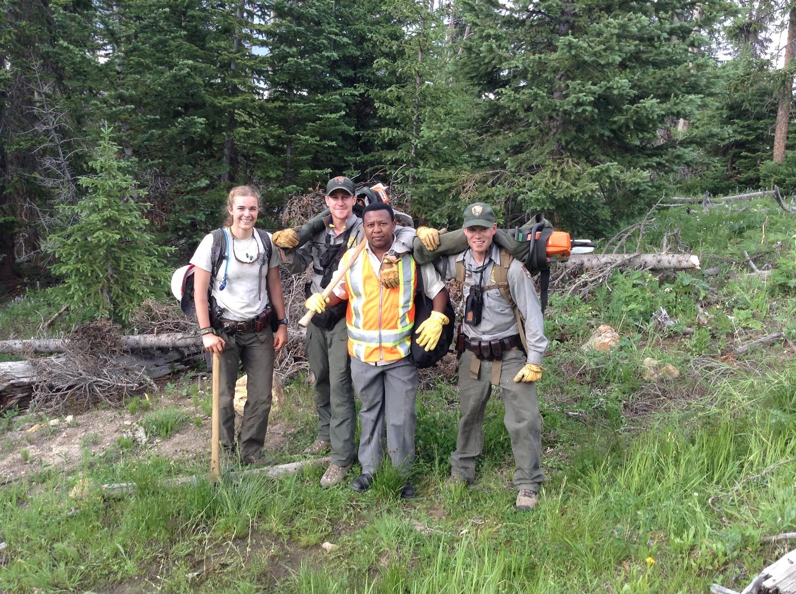four young people posing for picture with trees in the back