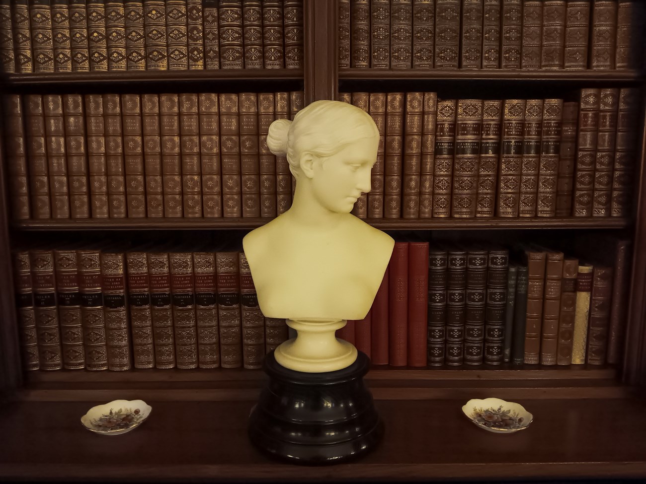 bust of the sculpture "The Greek Slave" in front of a shelf of historic books