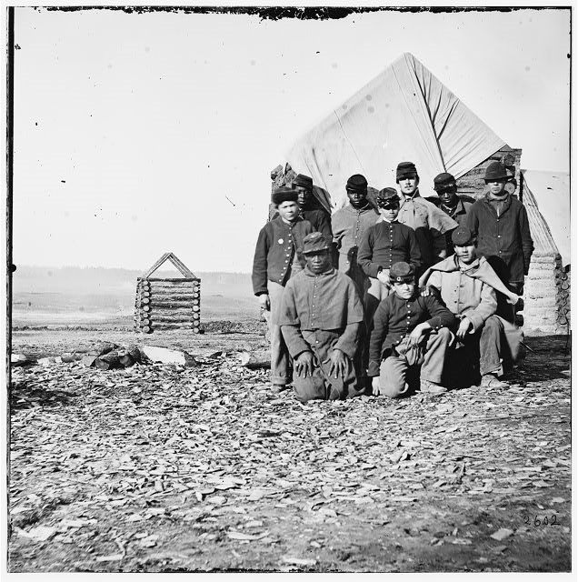 Group of Black and White Soldiers crouching and standing, posing for group photo.