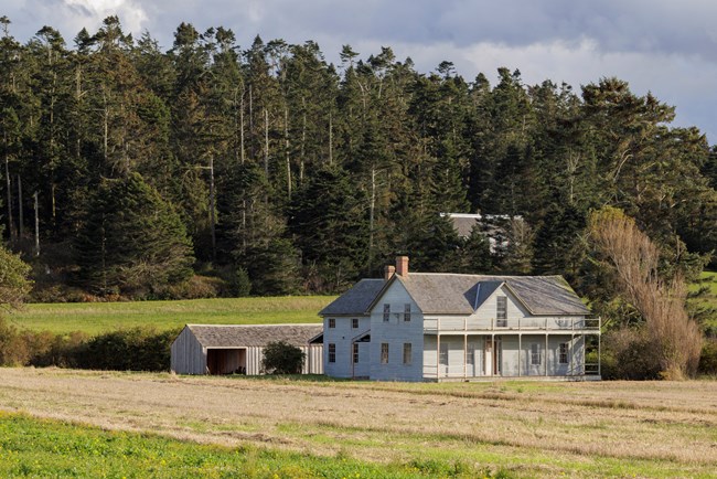 A house in a field with trees in the background.