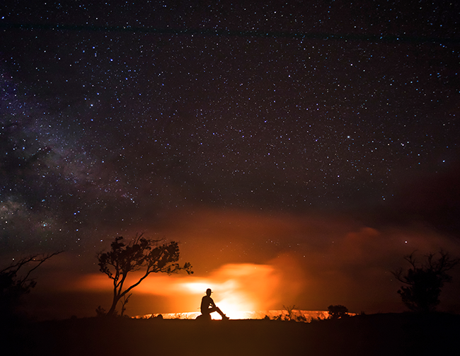 Silhouette of a ranger in front of a erupting volcano