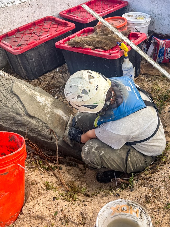 HPTC MAT crew member completing spall repair on the southern exterior face, facing the USS Missouri. Deteriorated concrete was removed, and a Hawaiian Cement mixture was applied to the area after cleaning.