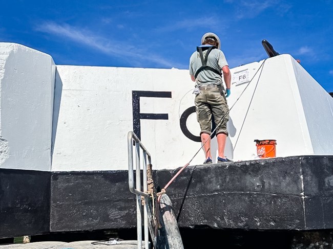 HPTC MAT crew member painting the F6 designation onto the quay.