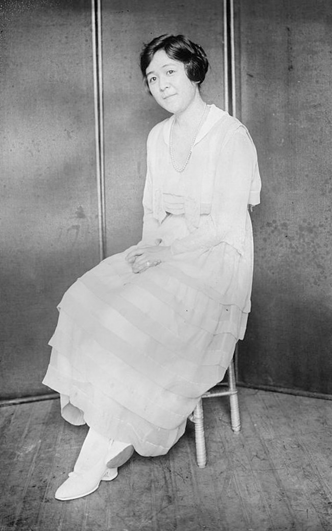 Japanese woman in flouncy white dress and coiffed hair sits for studio portrait