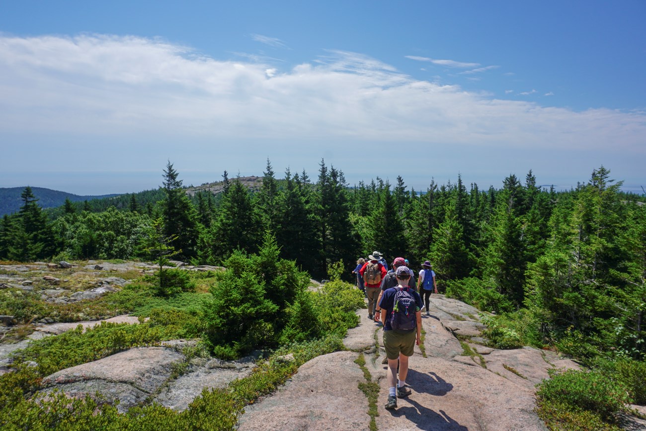 Volunteers hike the exposed rocky trail toward Penobscot Mountain’s summit.