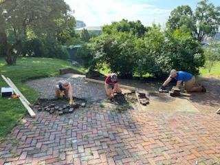 Historic Preservation Corps members repaving a brick pathway.