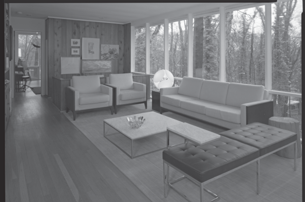 Black and white HABS photograph showing a large open living room with sofa and chairs on a rug and a wall of glass windows.